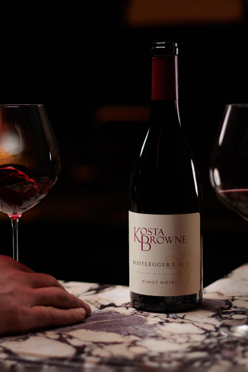 A bottle of Kosta Browne Pinot Noir at the winery with two glasses of wine.