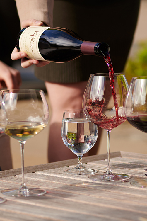 A woman pouring a bottle of Kosta Browne Pinot Noir at the winery in Sebastopol, CA.